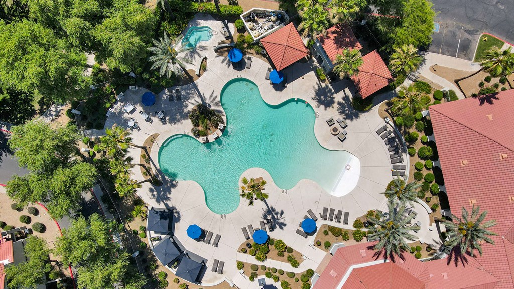 An aerial view of a resort with a large pool and palm trees.