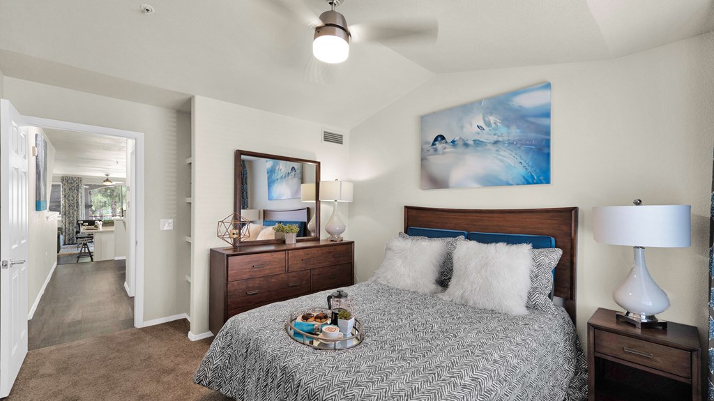 A bedroom with a bed, nightstand, and a painting on the wall.