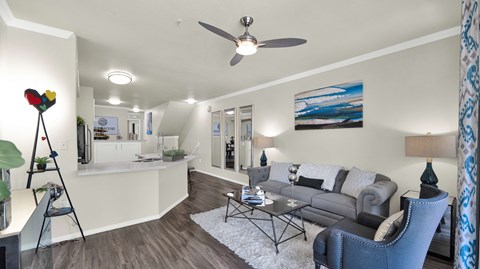 A living room with a grey couch and a painting on the wall.