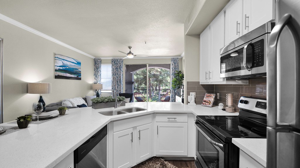 A modern kitchen with white cabinets and stainless steel appliances.