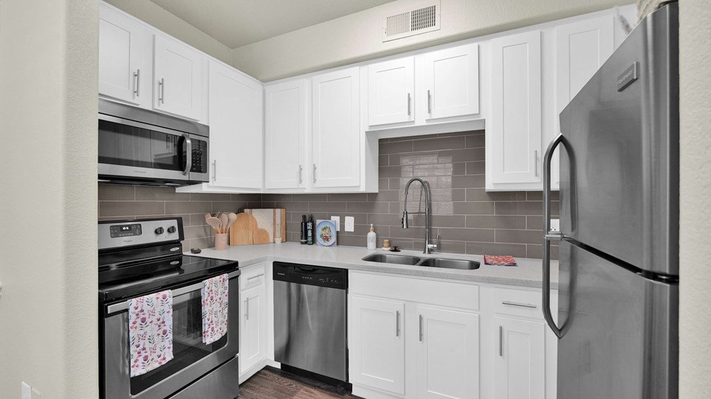 A kitchen with white cabinets and a stainless steel refrigerator.