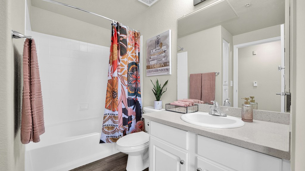 A bathroom with a white toilet, a white sink, and a shower curtain with a colorful design.