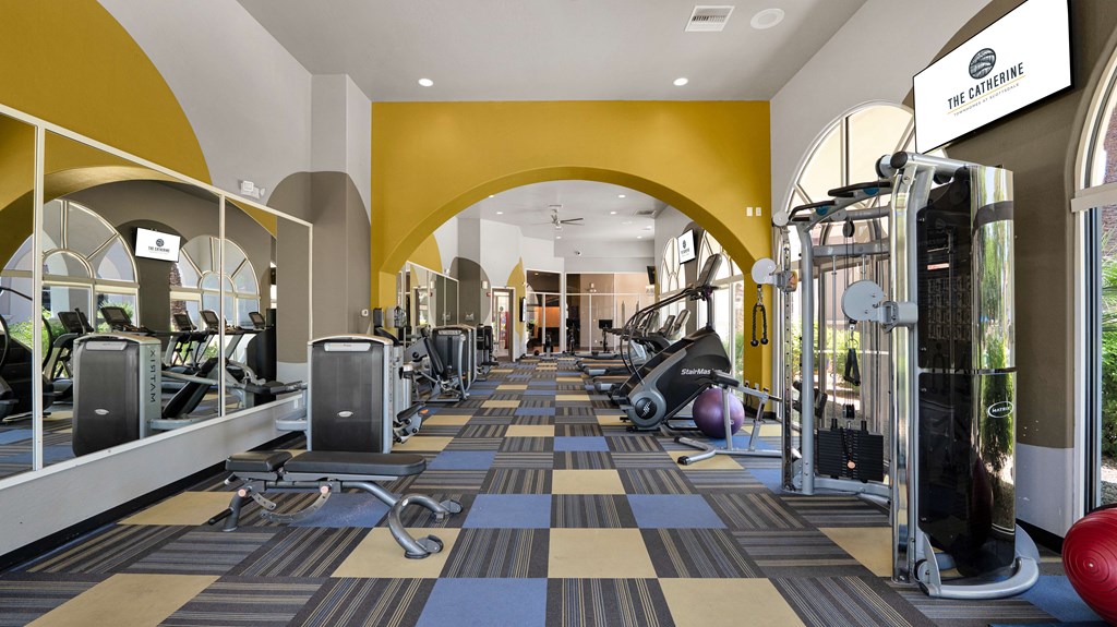 A gym with a variety of equipment including treadmills, weights and exercise machines.
