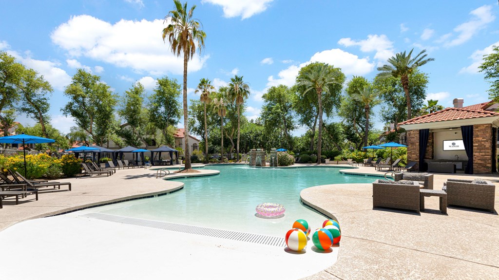 A pool with a blue sky and palm trees in the background.