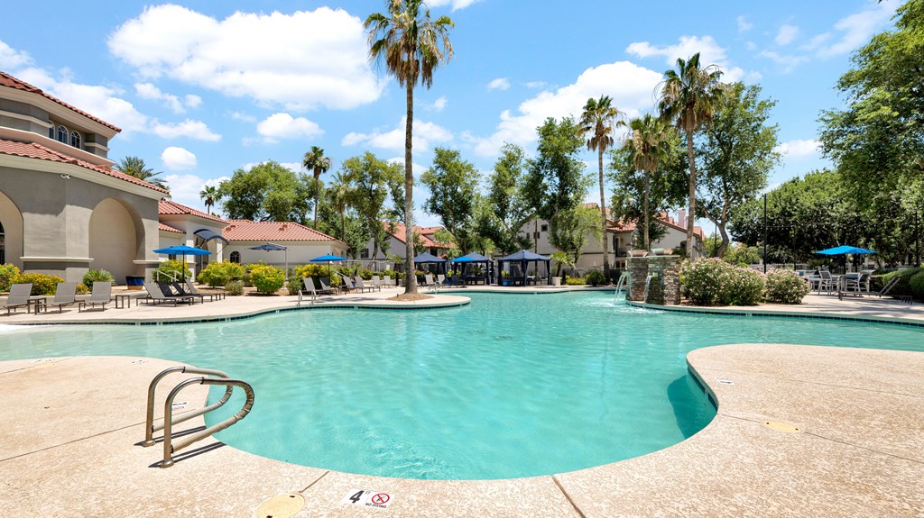 A large swimming pool surrounded by palm trees and lounge chairs.