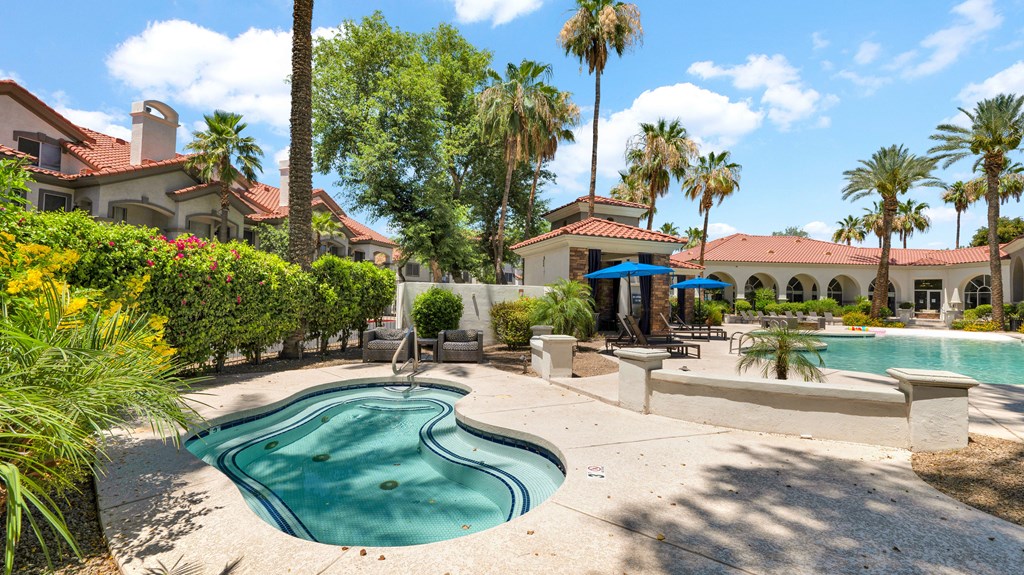 A pool surrounded by palm trees and a building in the background.