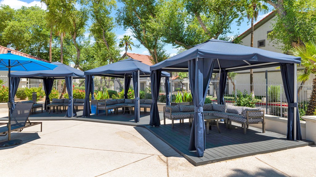 A patio area with blue canopies and benches.