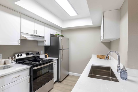 a white kitchen with stainless steel appliances and a sink