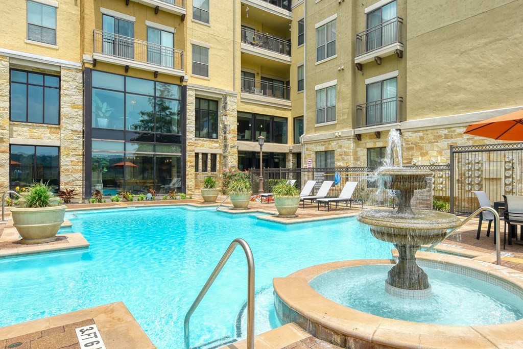 a swimming pool with a fountain in front of an apartment building