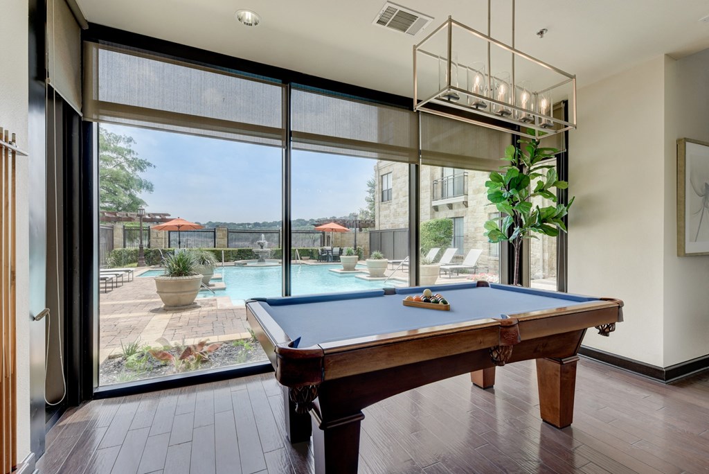 a pool table in a room with a view of a swimming pool