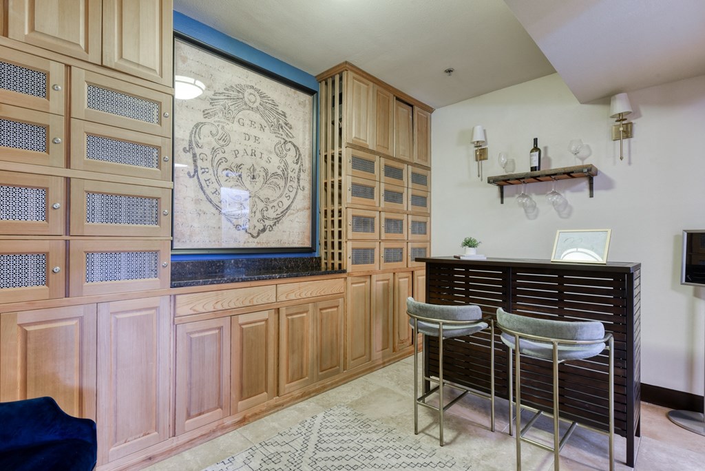 a bar with three stools in a room with wooden cabinets