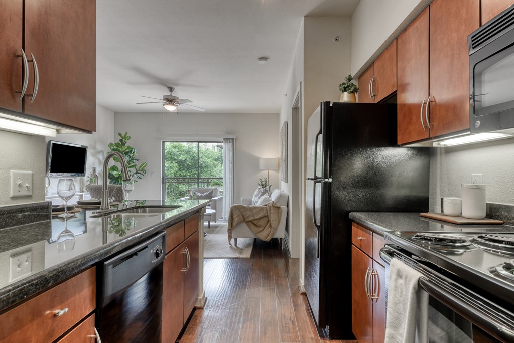 an open kitchen with black appliances and wood cabinets