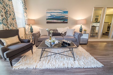 A living room with a grey couch, a coffee table, and a painting on the wall.