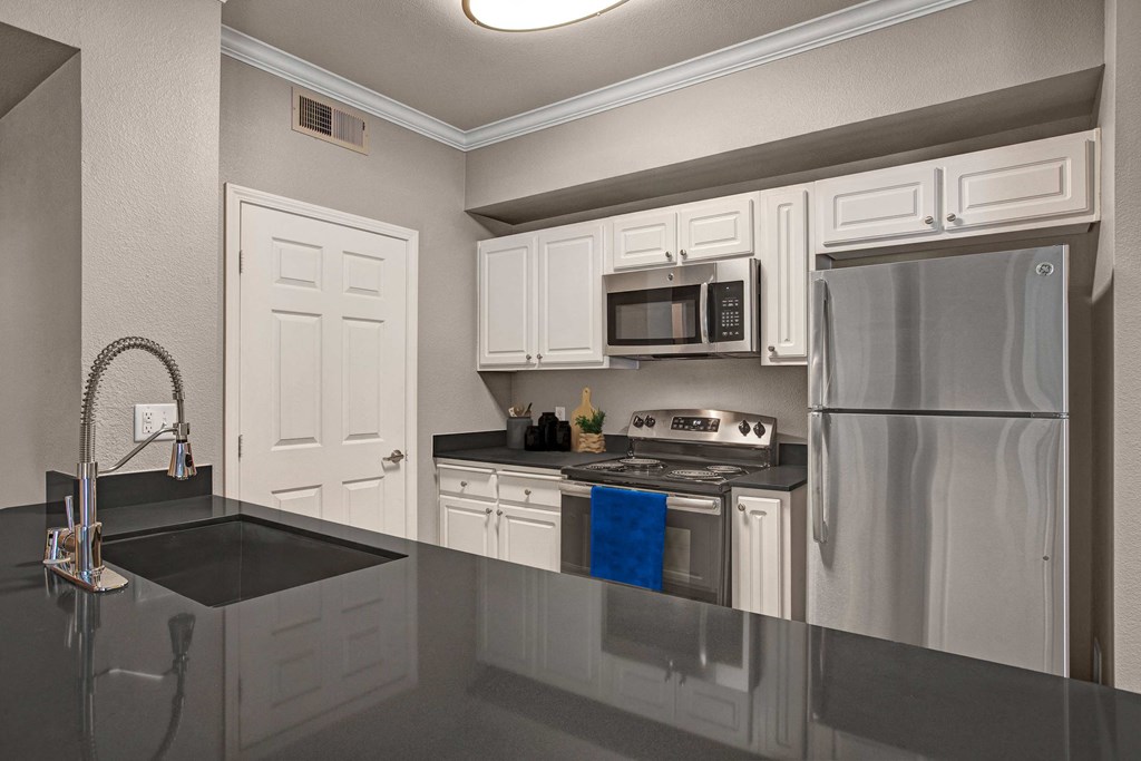 A kitchen with white cabinets and a black counter top.