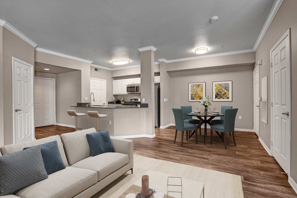 A modern living room with a grey couch and a dining table set up.