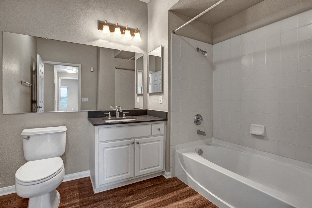 A white toilet is in a bathroom with a white tub and a white sink.