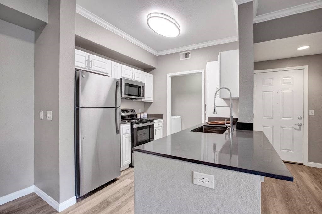 A kitchen with a black countertop and stainless steel appliances.