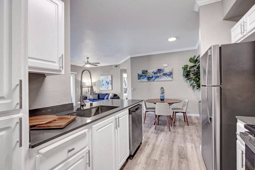 A kitchen with white cabinets and a wooden table.