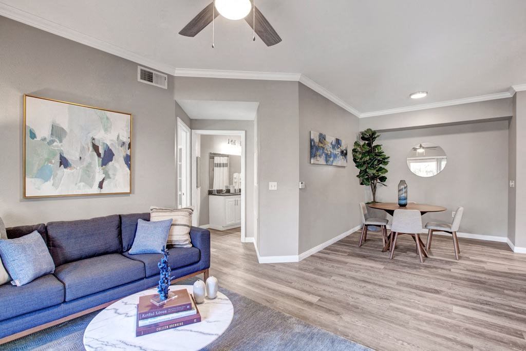 A living room with a blue couch and a painting on the wall.