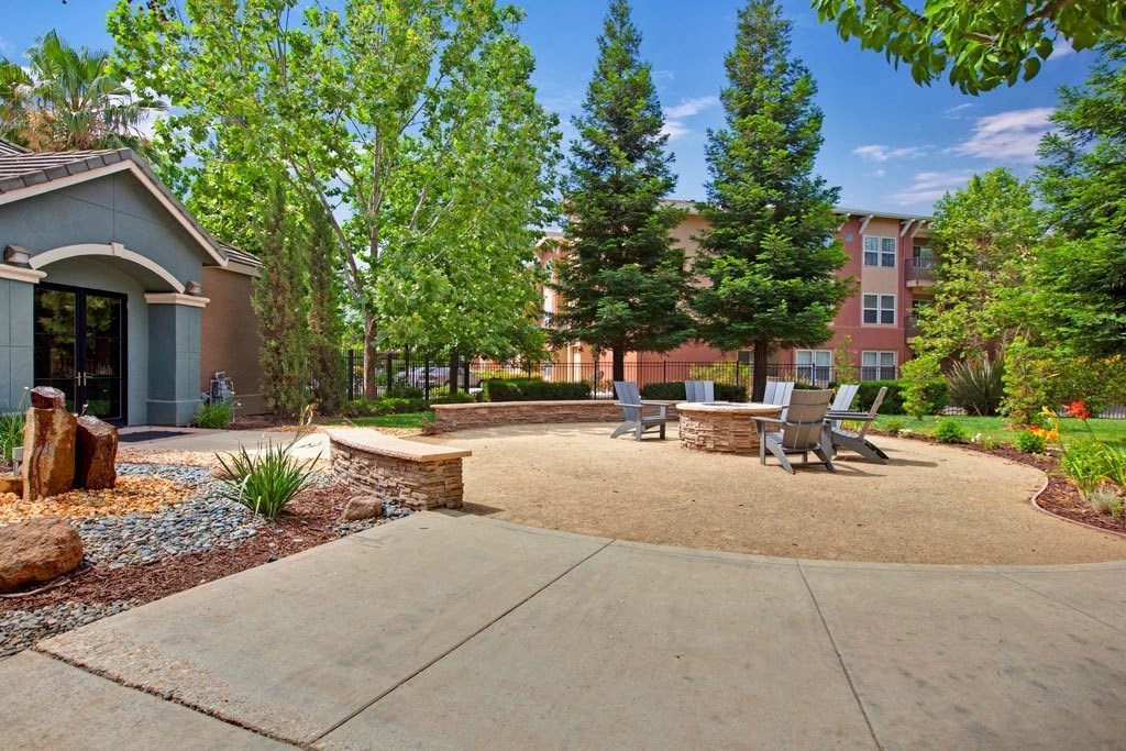 A sunny day at a residential area with a house, trees, and a patio.