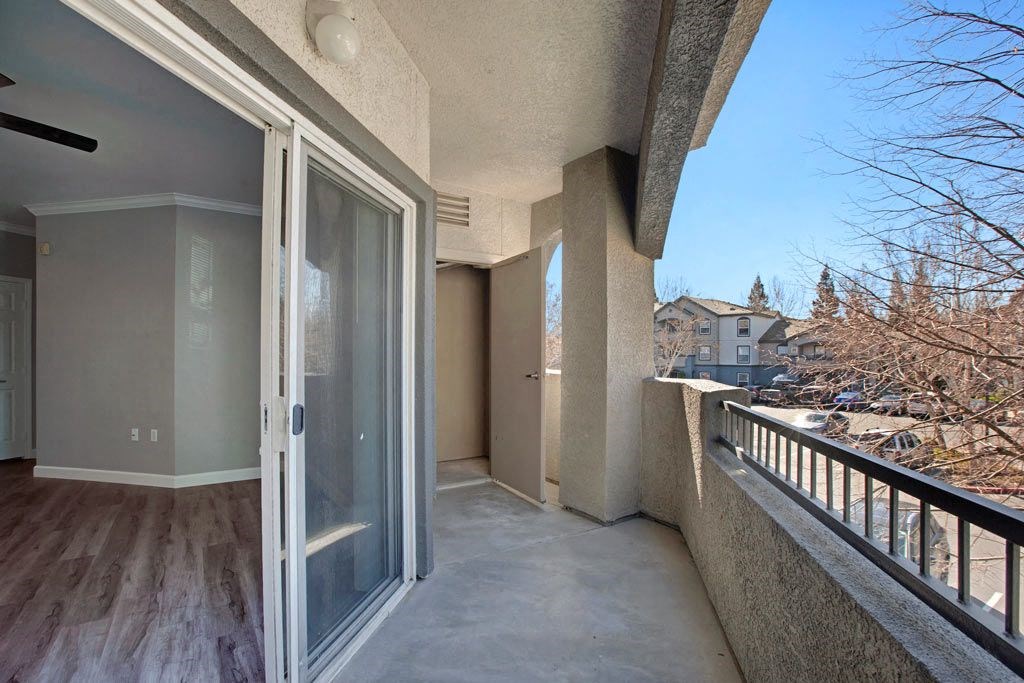 A balcony with a glass door and a concrete wall.