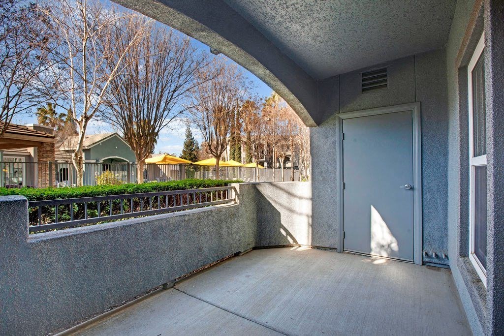 A concrete patio with a door and a wall.
