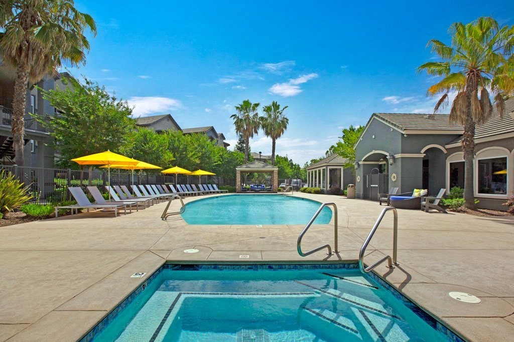 A swimming pool surrounded by palm trees and lounge chairs.