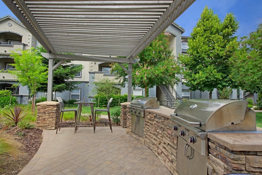 A patio with a grill and a stone wall.