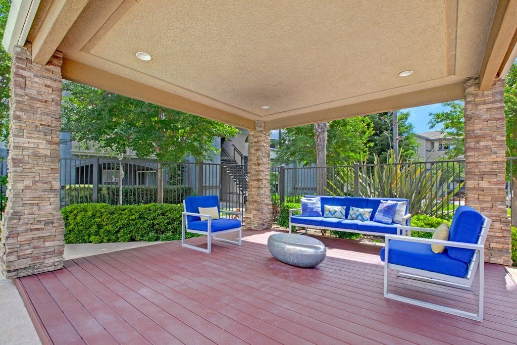 A patio with a red floor and blue chairs.