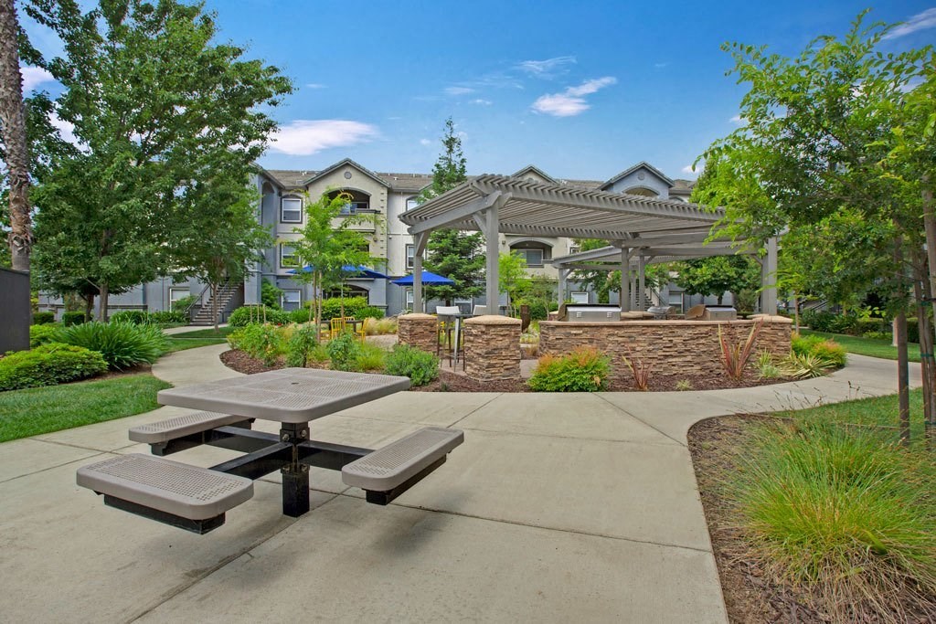 A concrete picnic table is in the middle of a concrete walkway.