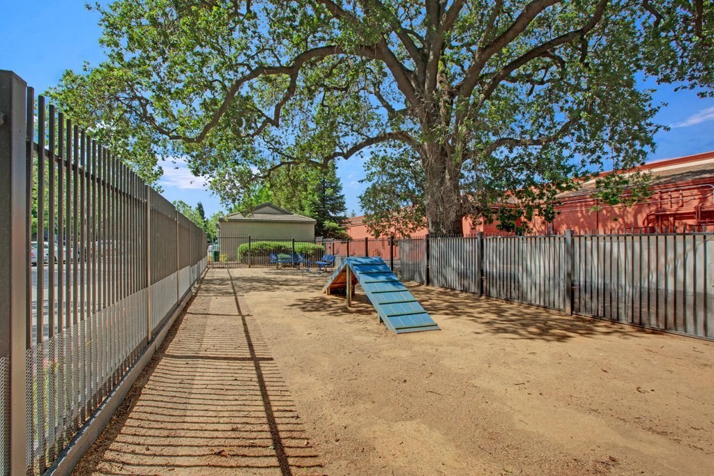 A playground with a slide and a sandbox is enclosed by a fence.