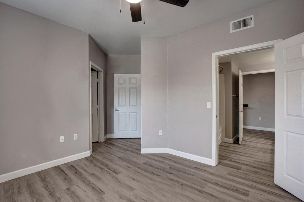 A room with a white door and a ceiling fan.
