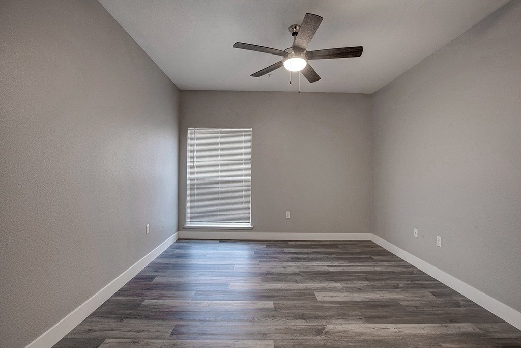 A room with a ceiling fan and a window with blinds.