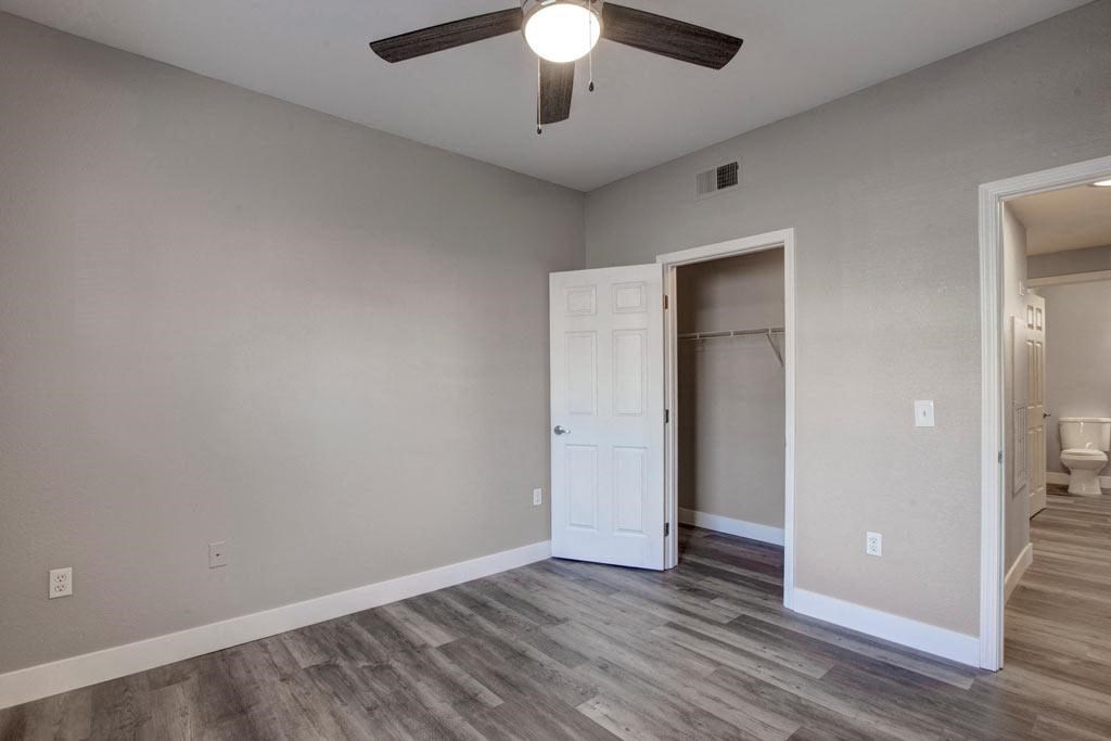 A room with a ceiling fan and a doorway leading to another room.