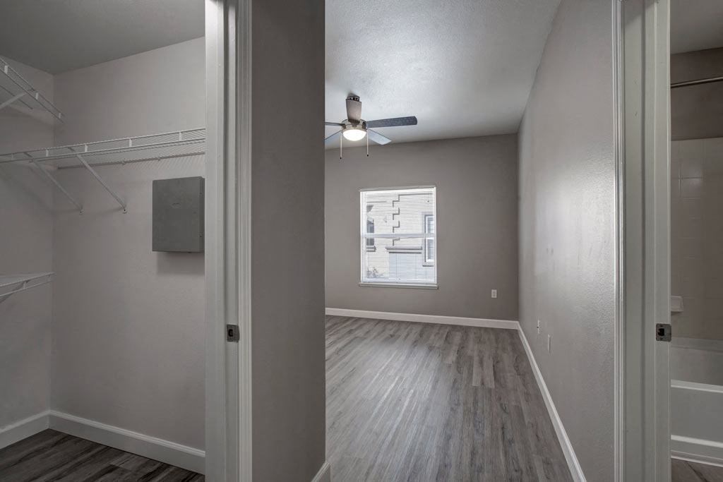 A room with a ceiling fan and a small window.
