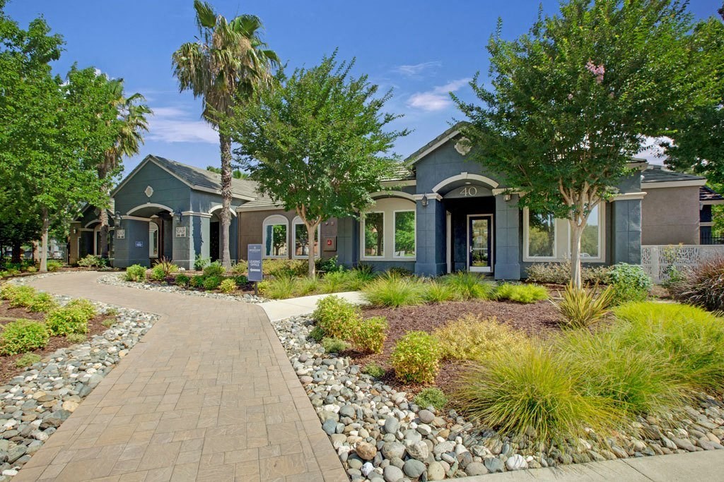 A building with a blue door and a sign that says 30 is surrounded by trees and plants.