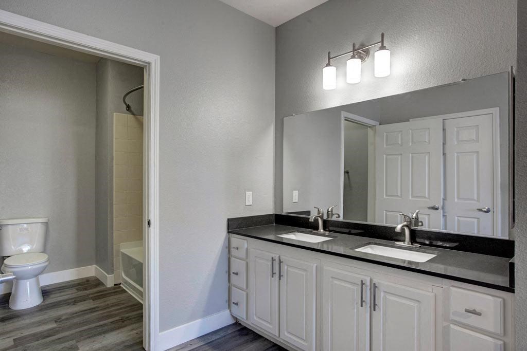 A bathroom with a toilet, sink, and mirror.