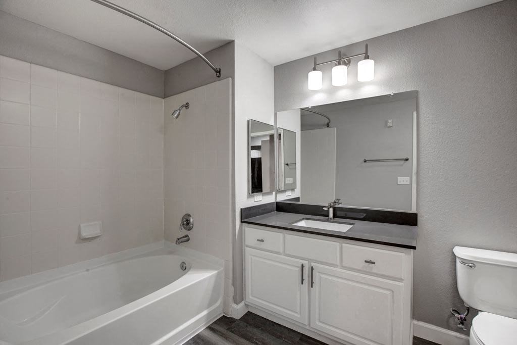 A white bathroom with a tub, sink, and mirror.