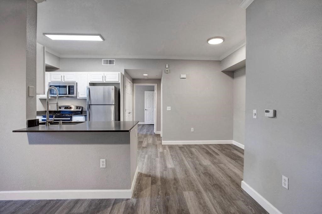 A kitchen with a refrigerator, microwave, and oven is visible through a glass door.