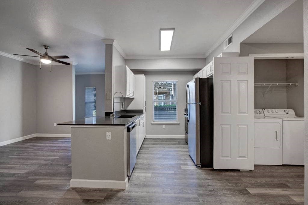 A kitchen with a black counter top and white cabinets.