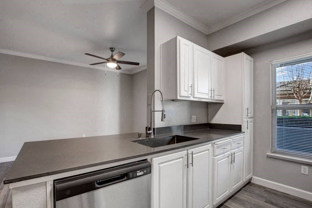 A kitchen with white cabinets and a black countertop.
