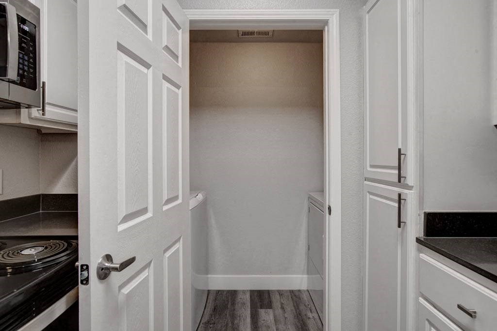 A white kitchen with a doorway leading to a hallway.