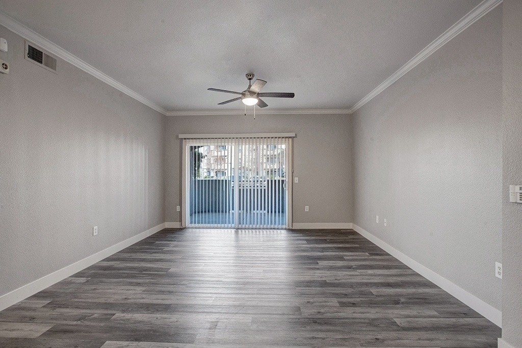 A room with a ceiling fan and sliding glass doors.