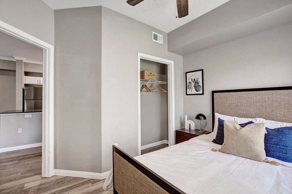 A bedroom with a bed, a ceiling fan, and a closet with a mirror.