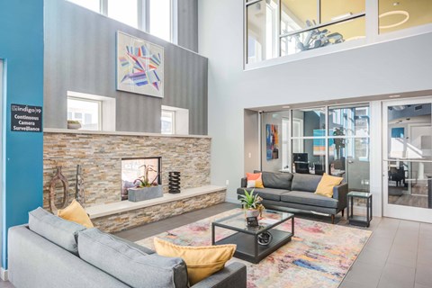 A living room with a grey couch and a stone fireplace.