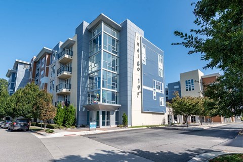 A modern multi-story building with a parking lot in front.