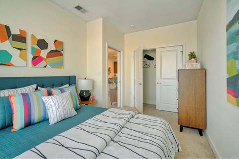 A bedroom with a blue bed and a wooden cabinet.