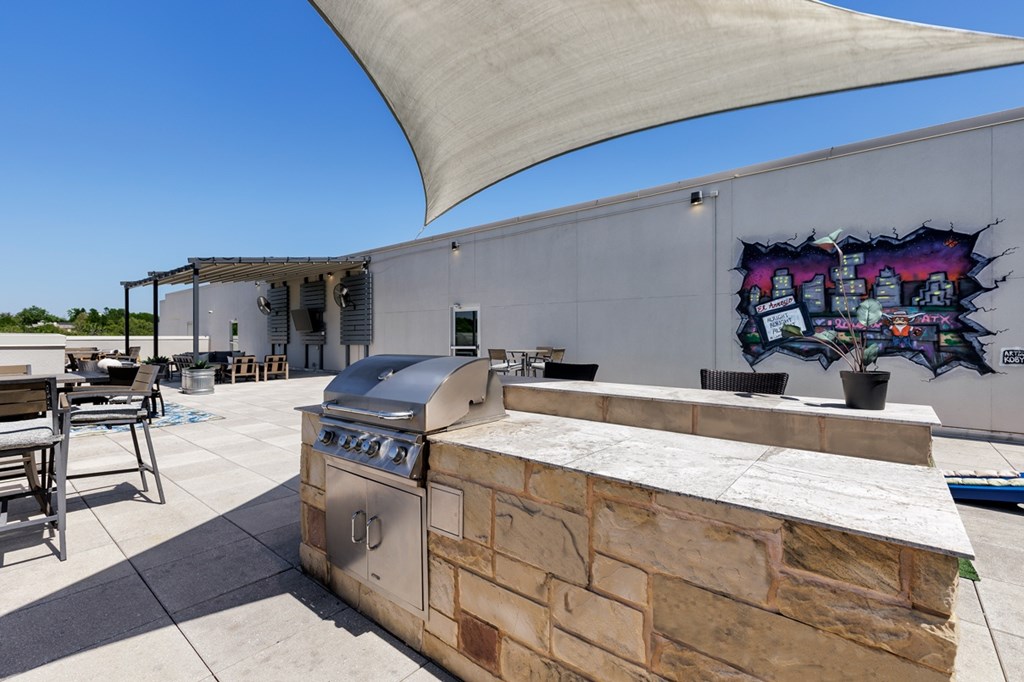 A barbecue grill is on a patio with a mural on the wall.