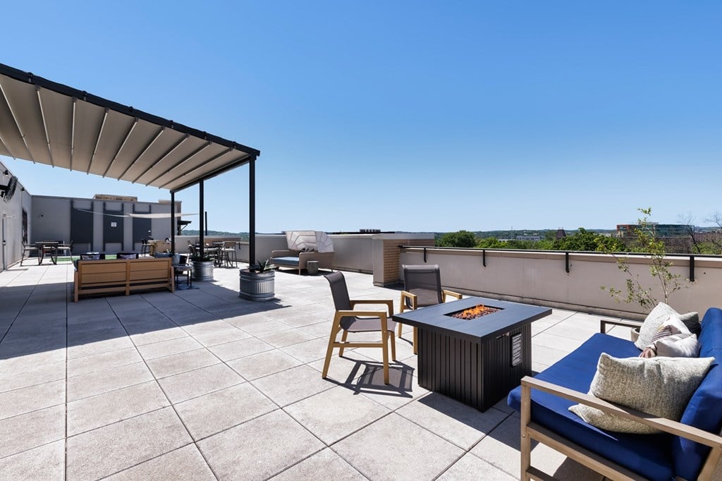 A patio with a table, chairs, and a fire pit.