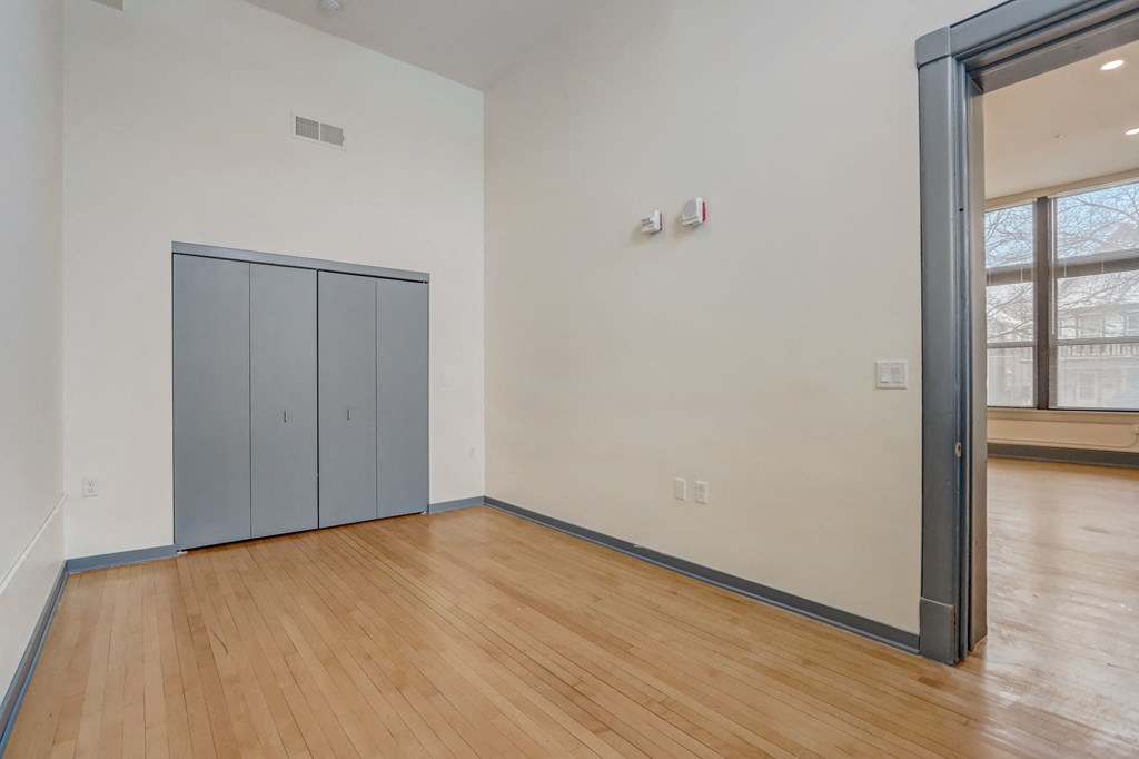 an empty living room with wood flooring and a door to a closet
